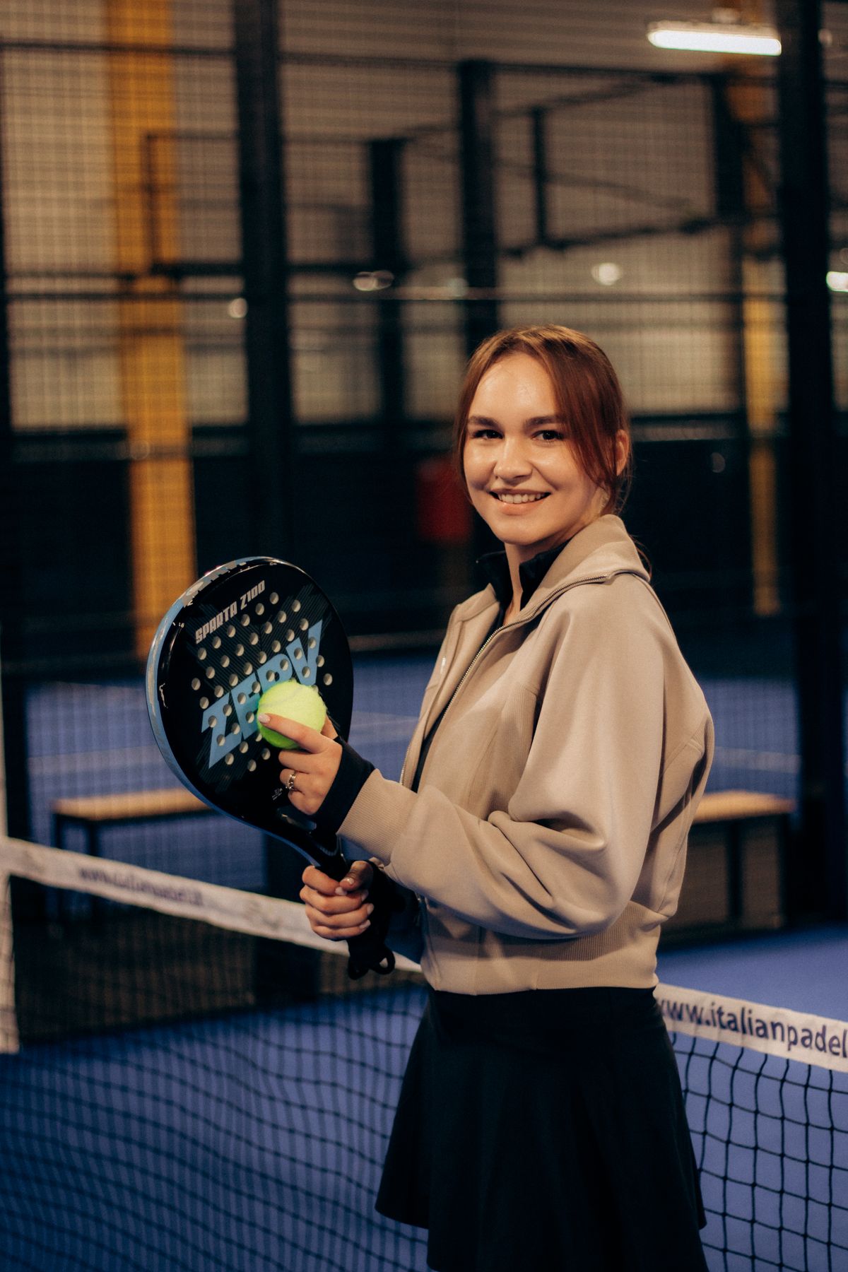 Jugadora sonriendo con su pala en la pista de pádel